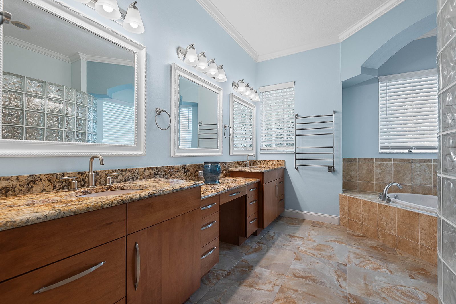 Primary bath with dual granite vanities, walk-in tile shower, and soaking tub