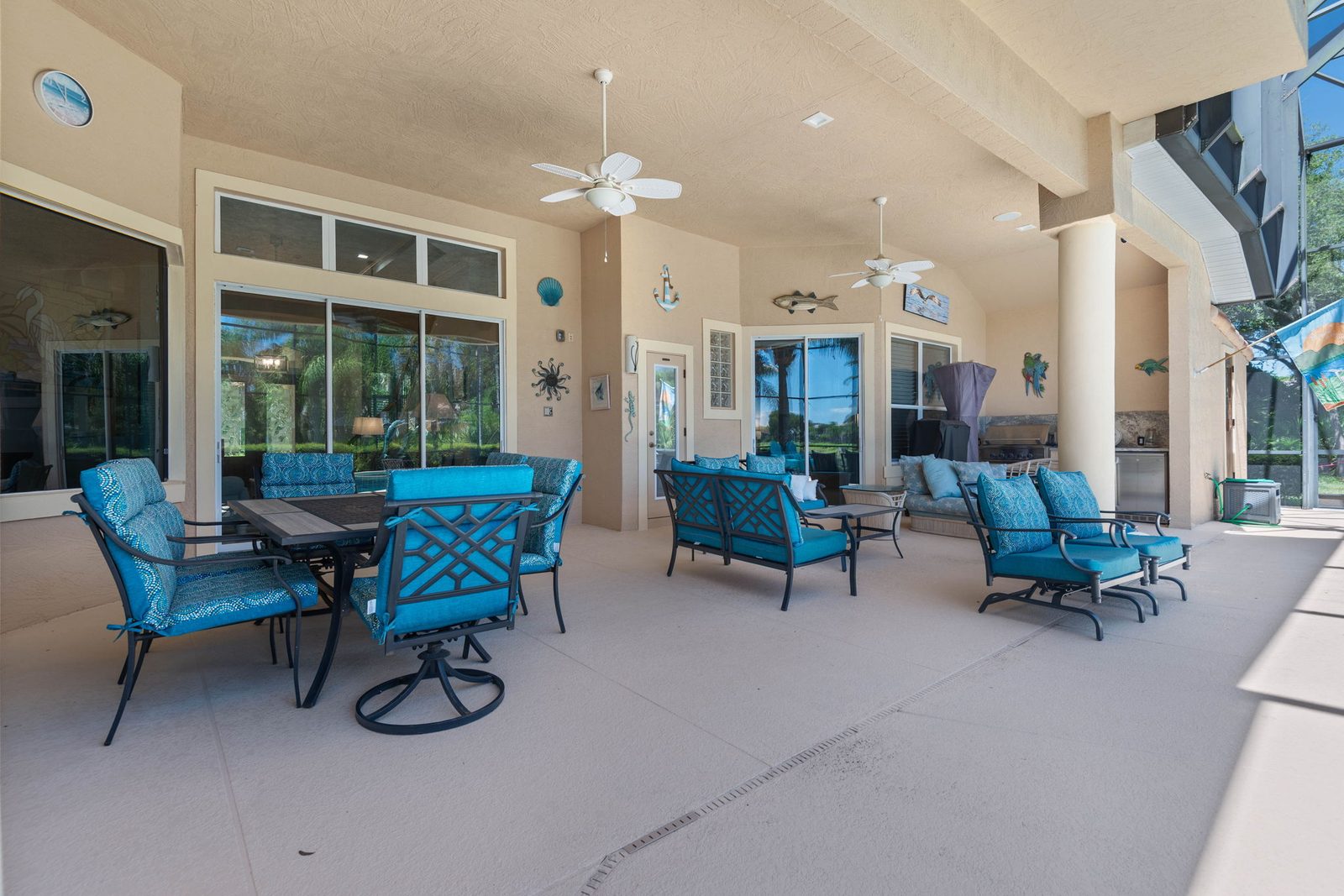 Covered outdoor lounge and dining area with summer kitchen and pool views